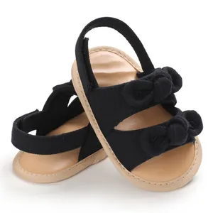 Détail des sandales de marche pour bébé en tissu noir avec semelle souple et nœuds mignons.