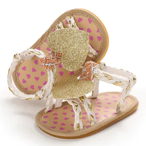 Detailed view of baby girl summer sandals with glittery gold heart and braided straps.