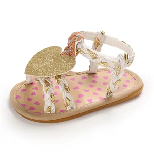 Close-up detail of baby girl sandals with gold glitter heart and braided straps.