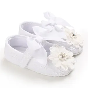 Detail of white lace infant princess shoes with delicate ribbon bows and floral accents