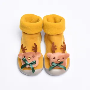 Close-up of baby walking shoes featuring a plush 3D reindeer design and green ribbon bows
