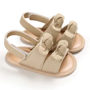 Détail de sandales de marche souples pour bébé en toile beige avec nœuds décoratifs