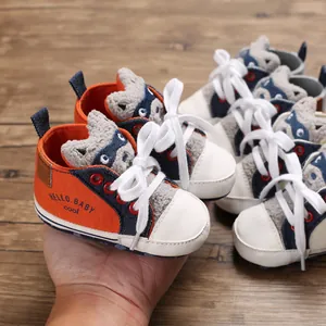 Detailed view of orange and denim infant walker shoes with soft cartoon raccoon patch