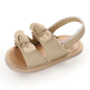 Gros plan de sandales beige pour bébé avec nœuds mignons et tissu en toile respirant.