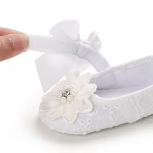Detailed close-up of white lace baby princess shoe featuring velcro strap and pearl flower