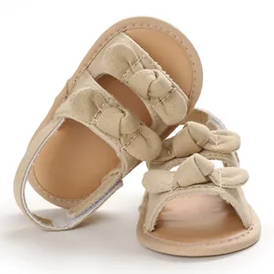 Vue détaillée de sandales pour bébé en toile beige avec semelle souple et nœuds