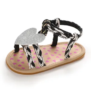 Close-up of baby girl summer sandal featuring a silver glitter heart and braided straps