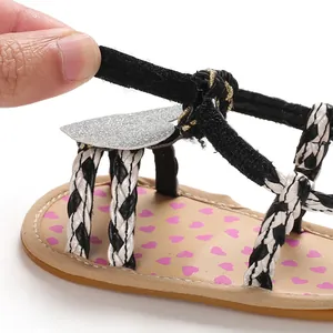 Detail view of baby girl sandal featuring adjustable velcro strap and heart patterns.
