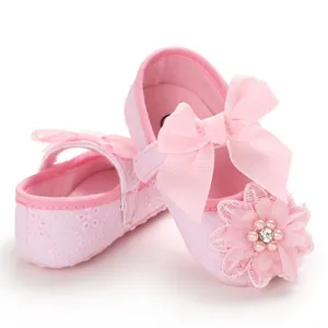 Close-up detail of pink lace baby walker shoes with ribbon bow and soft pearl flower