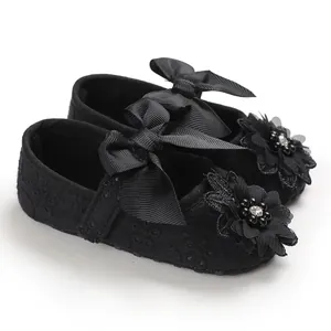 Detailed view of black lace baby princess shoes with elegant ribbon bow and flower