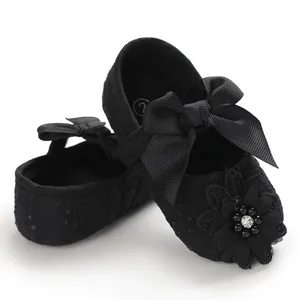 Detailed view of black lace baby Mary Jane shoes with ribbon bow and flower accent.