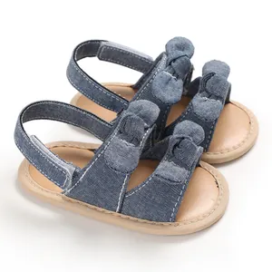 Détail de sandales en denim pour bébé avec des nœuds mignons et des semelles souples.
