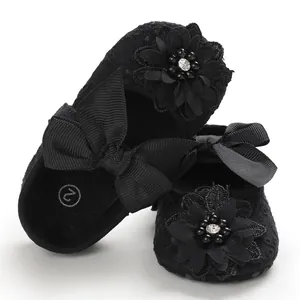 Detailed view of black baby princess shoes with elegant lace flower and bow accents.