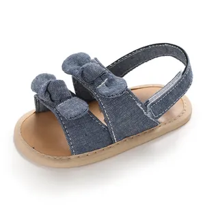 Gros plan de sandales de marche pour bébé en denim bleu avec double nœud et semelle souple.