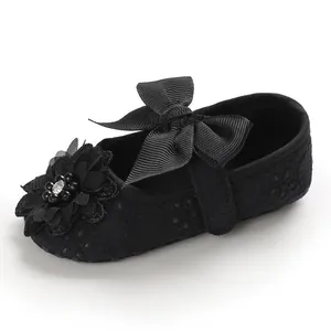 Close-up of black lace baby princess shoes with ribbon bow and flower detail