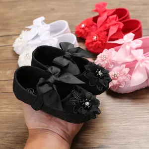 Detailed view of black baby princess shoes featuring a satin ribbon bow and flower
