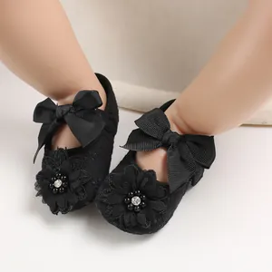Close-up of black lace baby walker shoes featuring elegant bows and flower details