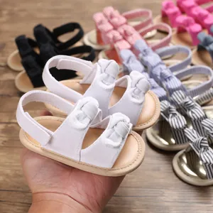 Détail de sandales blanches pour bébé avec semelle souple et nœuds multicolores
