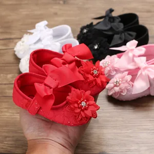 Detailed macro shot of red baby princess walking shoes featuring ornate bow and floral beadwork