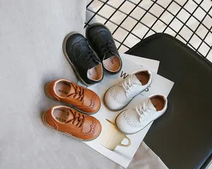 Detail shot of elegant children's leather brogue shoes in black, brown and white colors