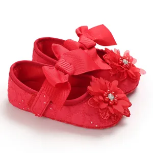 Detailed view of red soft-sole baby princess shoes with ribbon bows and floral accents