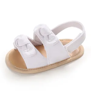 Vue rapprochée de sandales de marche pour bébé blanches avec nœuds et semelle souple.
