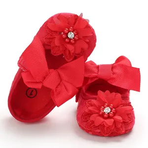 Close-up of red baby princess shoes featuring delicate lace, large bow, and flower rhinestone