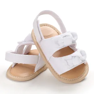 Vue détaillée de sandales blanches pour bébé avec semelle souple et jolis doubles nœuds