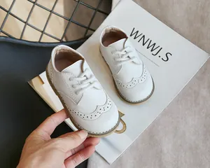 Close-up of white children's leather brogue shoes with elegant wingtip perforated details