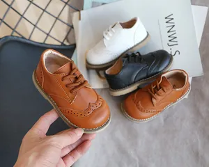 Close-up showing the detail of children's leather brogue shoes in brown, black, and white