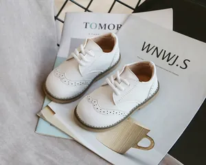 Detailed view of white brogue children shoes with classic perforated design and laces