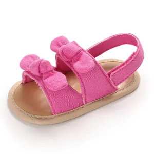 Détail rapproché de jolies sandales roses pour bébé fille avec double nœud et semelle souple