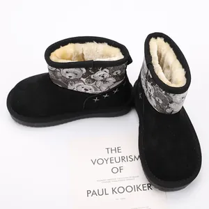 Detail of children's black snow boots with warm faux fur lining and bear pattern