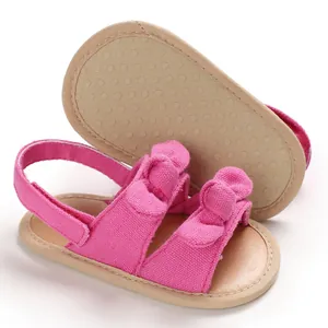 Détail de sandales roses pour bébé avec semelle souple antidérapante et nœuds