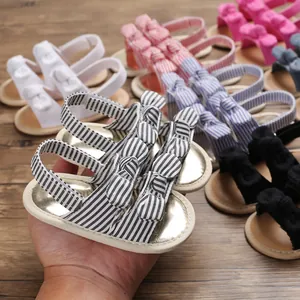 Détail de sandales pour bébé à semelle souple avec nœuds en diverses couleurs et rayures