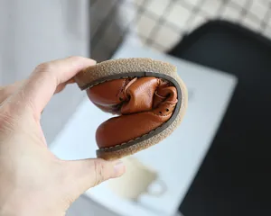 Detail showing the flexibility and soft leather of a child's brown loafer shoe.