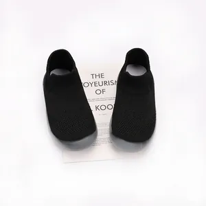 Detailed view of breathable black knit toddler sock shoes with flexible grey soles.