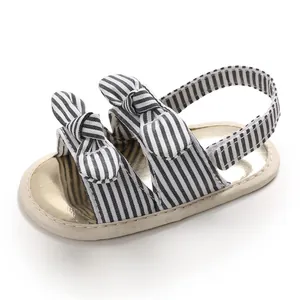 Gros plan de sandales pour bébé à rayures noires et blanches avec des nœuds décoratifs.