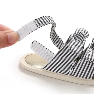 Vue détaillée de la bride Velcro réglable sur une sandale rayée pour bébé à semelle souple.
