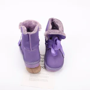 Detailed look at purple kids' winter boots featuring ribbon bows and warm fur lining.