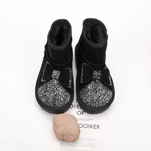 Close-up of black children's winter snow boots featuring a glittery bow and warm fur lining