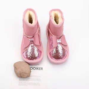 Detailed view of pink glitter children's snow boots with decorative bows and fur lining
