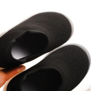 Close-up detail of breathable knit fabric on black toddler sock shoes with soft sole.