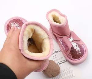 Close-up of pink children's snow boots with thick faux fur lining and bow detail