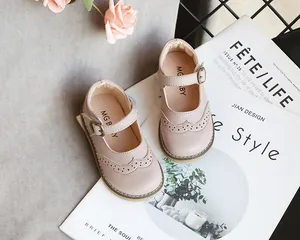 Detailed macro view of pink girl's Mary Jane leather shoes featuring brogue details