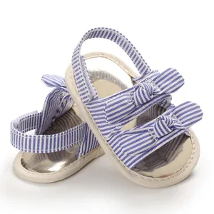 Détail des sandales de marche pour bébé à rayures bleues et blanches avec nœuds décoratifs