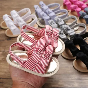 Gros plan de sandales d'été rayées rouges pour bébés de 0 à 1 an avec double nœud.