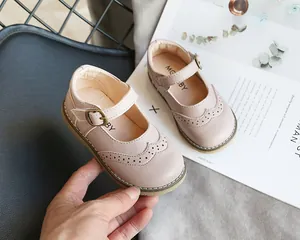 Detail shot of pink girl's Mary Jane shoes with brogue patterns and soft leather.