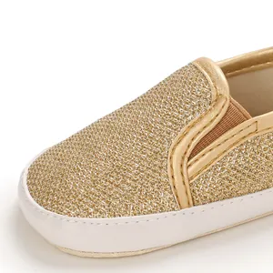 Dettaglio ravvicinato di una scarpa glitterata dorata per neonati con suola morbida.