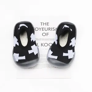 Breathable baby sock shoes with white cross pattern on black fabric, soft sole for toddlers.